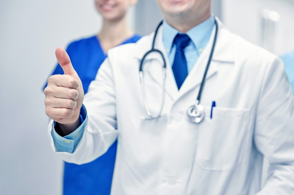 close up of doctors at hospital showing thumbs