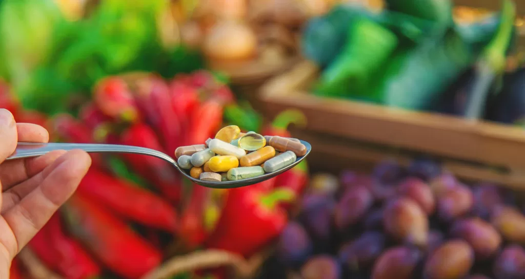 Vitamins and supplements in a spoon with vegetables. Selective focus.